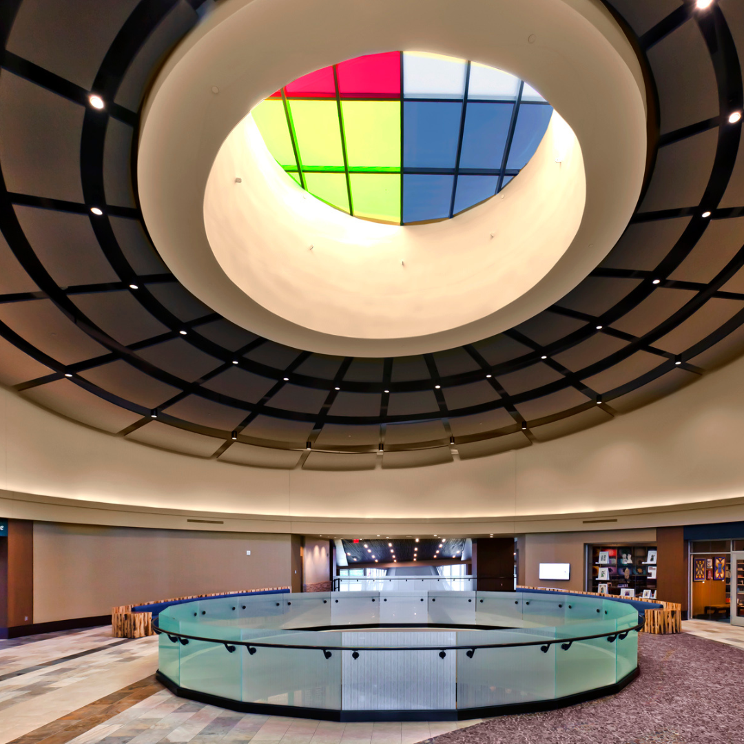 Architectural interior with a circular skylight and colorful glass.